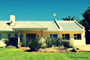 una casa amarilla con techo verde en Kududu Guest House, en Addo