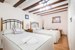Habitación con 2 camas, paredes blancas y techos de madera. en Casa La Carpintera, en Royuela