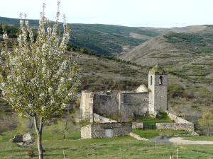 an old building on the side of a hill with a tree at La Colmenita in Navalsaz
