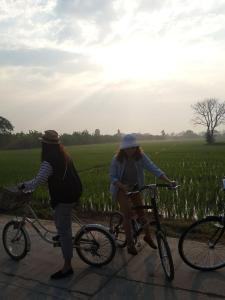 two women riding bikes in front of a field at Baangaimuan in Lamphun