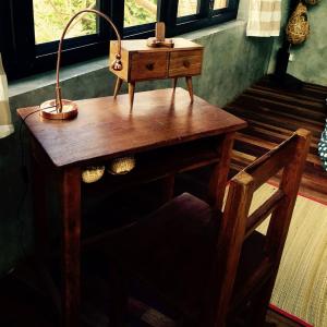 a wooden desk with a lamp and a chair at Baangaimuan in Lamphun