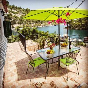 a table and chairs with a green umbrella on a balcony at Alma Libre in Gaios