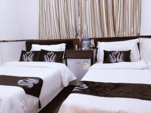 2 Betten mit schwarzer und weißer Bettwäsche in einem Zimmer in der Unterkunft Seasons Hotel - Causeway Bay in Hongkong