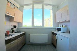 a kitchen with a window and a sink and a microwave at 54a Tselinogradskaia Str at Alekseevka underground in Kharkiv