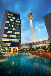 a view of a pool with a tower in the background at Oasia Suites Kuala Lumpur by Far East Hospitality in Kuala Lumpur