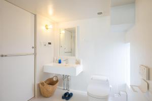 a bathroom with a sink and a toilet and a mirror at Uzu House in Shimonoseki