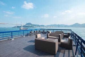 una terraza con sofás y sillas junto al agua en Uzu House, en Shimonoseki