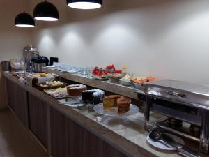 a buffet line with different types of cakes and desserts at Hotel Nova Geração in Santa Luzia