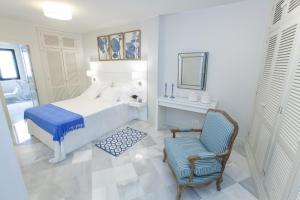 biała sypialnia z łóżkiem i krzesłem w obiekcie GR Suites Boutique Picasso w Maladze
