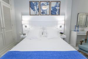 sypialnia z białym łóżkiem i niebieskim kocem w obiekcie GR Suites Boutique Picasso w Maladze