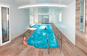 a woman laying in a swimming pool in a house at Appartement vue mer avec piscine intérieure in Larmor-Plage