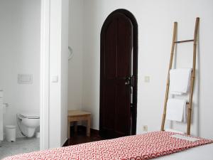 a bedroom with a bed and a bathroom with a toilet at Foral Guest House - Óbidos in Óbidos