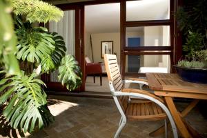 a patio with a wooden table and chairs and plants at Lézard Bleu Guest House in Cape Town +60 photos
