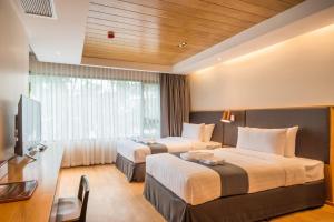 a hotel room with two beds and a television at Asana Hotel & Residence in Pattaya Central