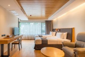 ein Hotelzimmer mit einem Bett und einem Wohnzimmer in der Unterkunft Asana Hotel & Residence in Pattaya