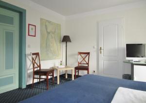 a bedroom with a bed and two chairs and a table at Hotel Ostseestern in Kühlungsborn
