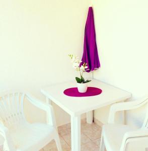 a white table with a vase with flowers on it at Apartment Emanuela in Rovinjsko Selo