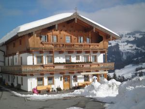 un gran edificio de madera con nieve alrededor en Hagauhof, en Kirchberg in Tirol