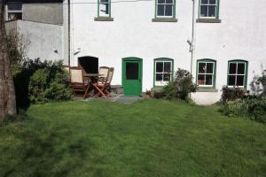 uma casa com duas cadeiras e uma porta verde em Delfryn Cottage em Rhayader