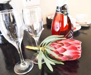 a table with two wine glasses and a flower on it at Travel Lodge Sabie in Sabie
