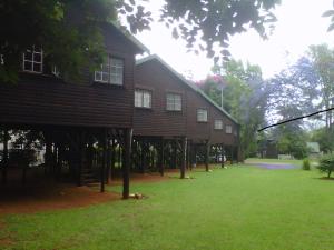 a large wooden house with a grass yard in front of it at Travel Lodge Sabie in Sabie