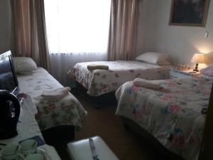 a hotel room with three beds and a window at Heila's in house Family room-Homestay! in Bloemfontein