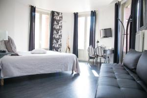 a bedroom with a bed and a couch at Hôtel et Restaurant Le Regina in Le Puy-en-Velay