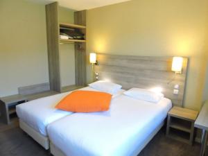 een slaapkamer met een wit bed met een oranje kussen erop bij Kyriad Auray in Auray