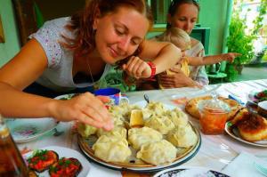 a woman sitting at a table with a plate of food at Guest House Dinara in Kaji-Say