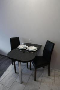 コウォブジェクにあるPoppy Apartment Kolobrzegの黒いテーブル(黒い椅子2脚付)とテーブル(眼鏡付)