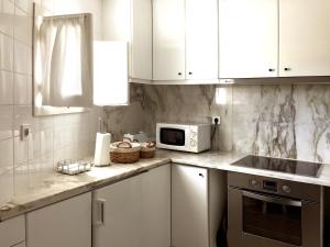 a kitchen with white cabinets and a microwave at Millhousedune in Cepães