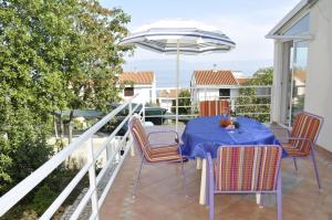 einen Tisch und Stühle auf einem Balkon mit Sonnenschirm in der Unterkunft Apartment Vesna in Ravni