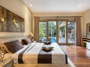 een slaapkamer met een groot bed en een glazen schuifdeur bij Exotica Bali Villa Bed and Breakfast in Canggu