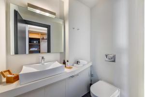 a white bathroom with a sink and a mirror at Naves Suites in Ermoupoli