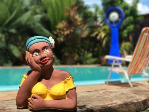 a plastic figurine of a woman in a yellow swimsuit by a pool at Pousada Casa Colorida in Porto De Galinhas