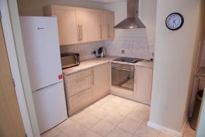 a kitchen with a white refrigerator and a clock on the wall at City Centre Luxury Holiday Apartment in Liverpool