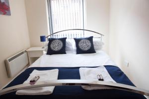 a bed with blue and white pillows and a window at City Centre Luxury Holiday Apartment in Liverpool