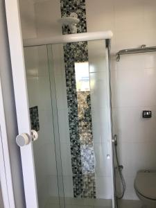 uma casa de banho com uma cabina de duche em vidro e um WC. em Pousada Mariá em Cabo Frio