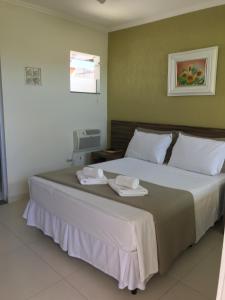 1 dormitorio con 1 cama grande y 2 toallas. en Pousada Mariá, en Cabo Frío