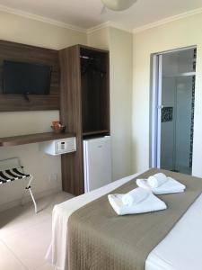 1 dormitorio con 1 cama con 2 toallas en Pousada Mariá, en Cabo Frío