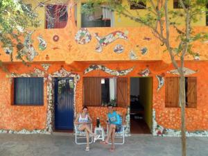 zwei Personen, die vor einem Gebäude auf Stühlen sitzen in der Unterkunft La Neofita in Mina Clavero