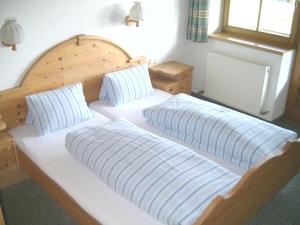 a bedroom with two beds and a wooden headboard at Pension Steinerhof in Oberau