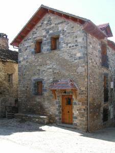 ein altes Steingebäude mit einer Holztür in der Unterkunft Casa lo Sastre - Jasa in Jasa