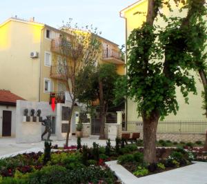 a building with a tree and flowers in a park at Apartments Nik in Selce