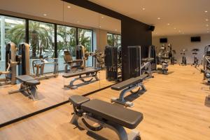 un gimnasio con una fila de máquinas de correr y espejos en AQUA Hotel Silhouette & Spa - Adults Only, en Malgrat de Mar