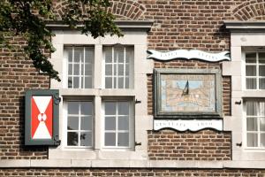 a clock on the side of a brick building at Abdij Hotel Rolduc in Kerkrade