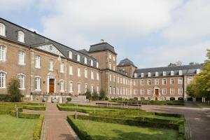 um grande edifício de tijolos com um parque em frente em Abdij Hotel Rolduc em Kerkrade