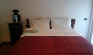 un letto rosso e bianco con lenzuola e cuscini bianchi di Suite210 a Trani