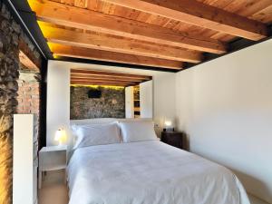 Saint MarcelにあるLe Coffretの白いベッドとレンガの壁が備わるベッドルーム1室が備わります。