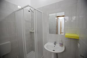 un bagno bianco con doccia e lavandino di Dimora Hostel a Agrigento